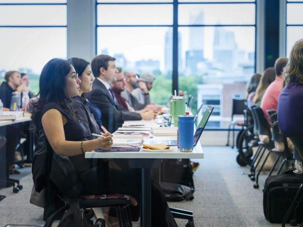 Classroom scene at Elon Law Flex Program, a part-time option at one of the top law schools in Charlotte. Students are in class with the Charlotte skyline seen through windows in the background.